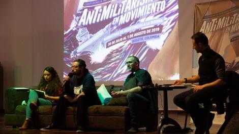 Four people sit in front of a screen with the words "Antimilitarism in Movement"