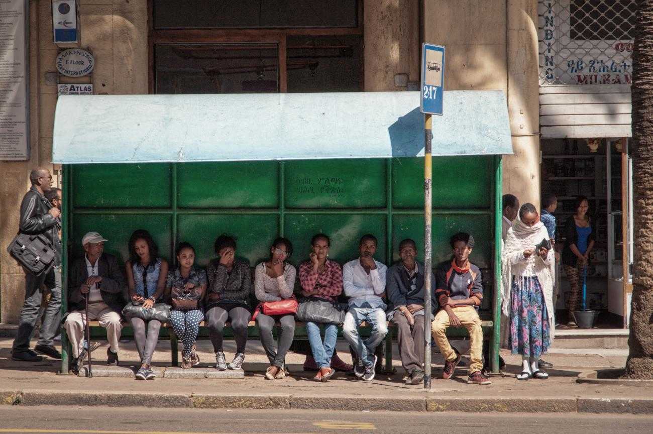 Leute, die an einer Bushaltestelle warten sitzen