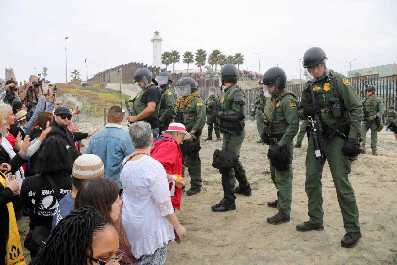 Los líderes religiosos intentan llevar a cabo una ceremonia de agua pidiendo que la paz con justicia regrese a la tierra mientras los agentes de la Patrulla Fronteriza de los Estados Unidos observan