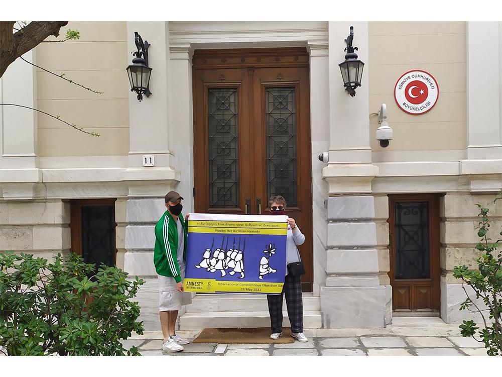 Two people holding a banner in front of a building