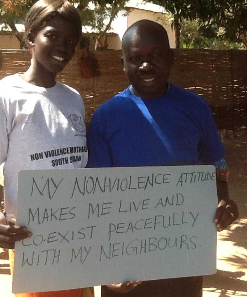Activists hold a sign saying "My nonviolence attitude makes me live peacefully and coexist with me neighbours"