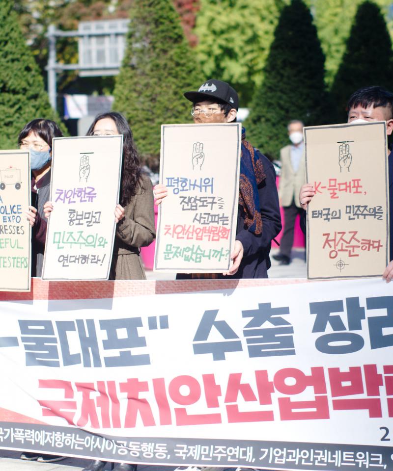 A number of Korean activists stand behind a large banner holding signs