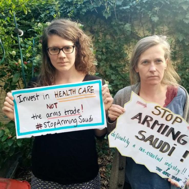Dos personas están sosteniendo carteles que dicen "Paren de armar a Arabia Saudita"