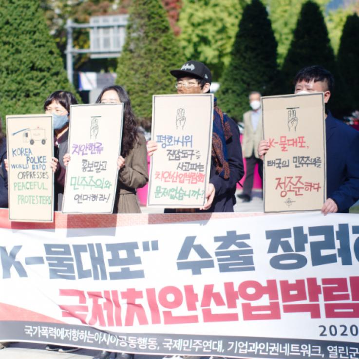 A number of Korean activists stand behind a large banner holding signs