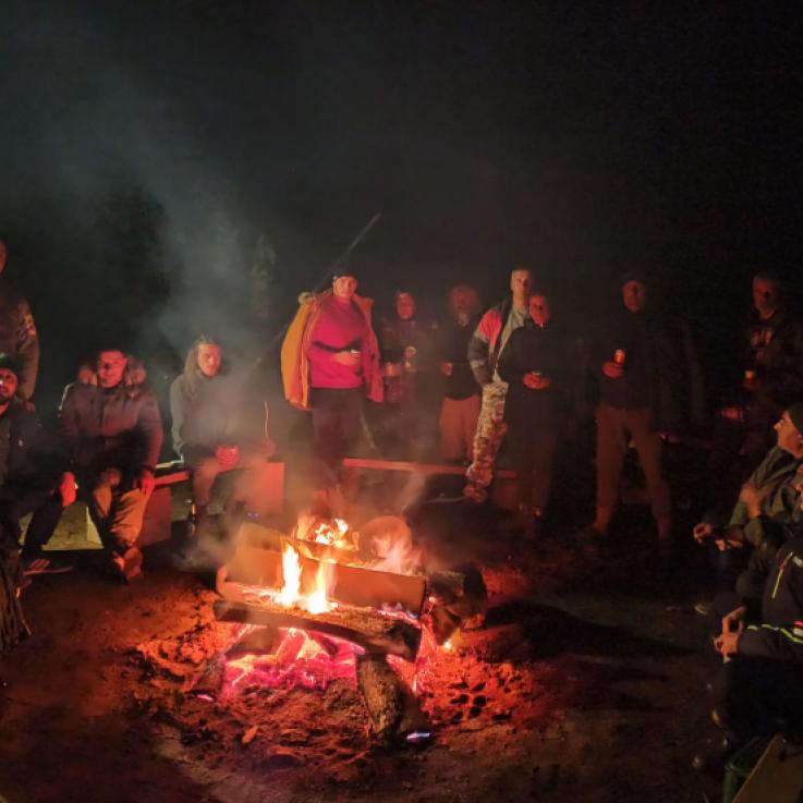 A large group of people sitting around a campfire at night