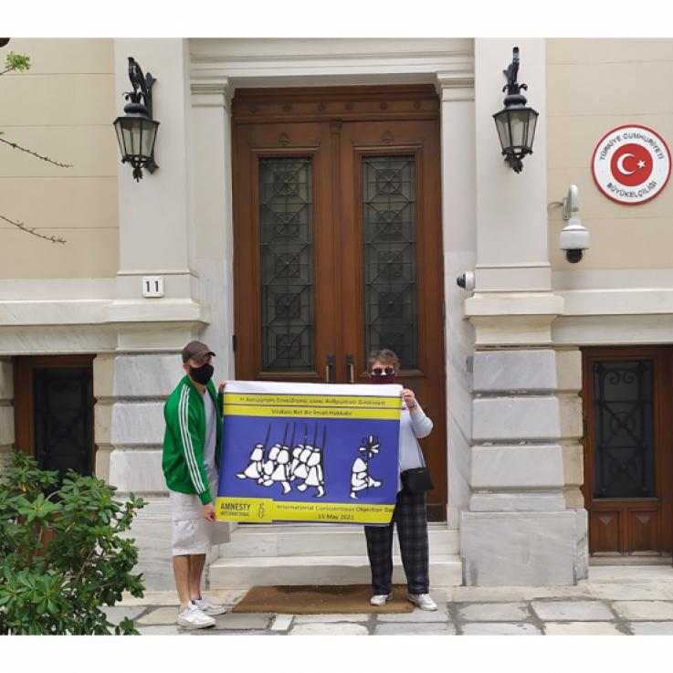Two people holding a banner in front of a building