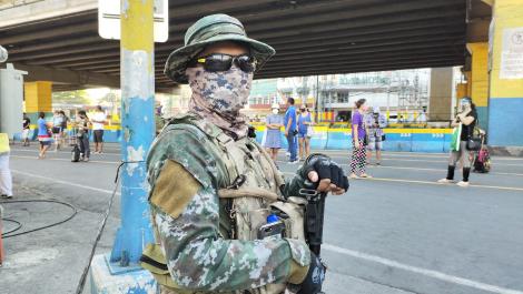 A soldier stood in the street wearing a face mask
