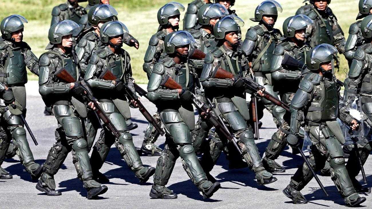 A large group of heavily armed and armoured police in Brazil during the world cup, march in formation.