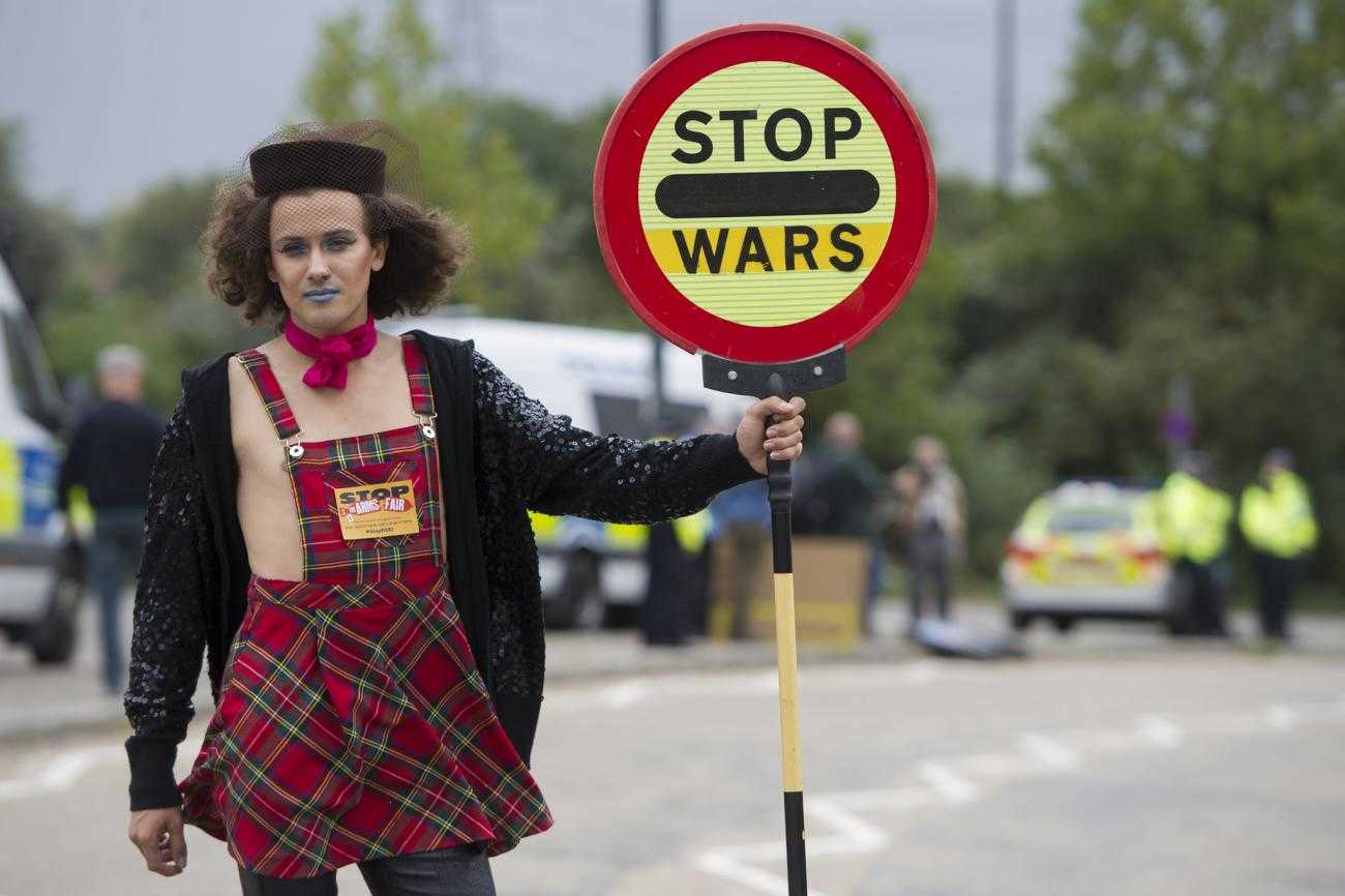 A person holds a street sign reading "stop wars"