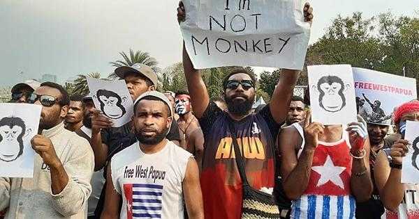 Varias personas se paran con máscaras de mono. Uno tiene un cartel que dice "No soy un mono"