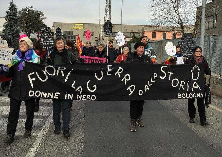 Four women from Women in Black Bologna hold a banner on a protest against the RWM factory in Ghedi