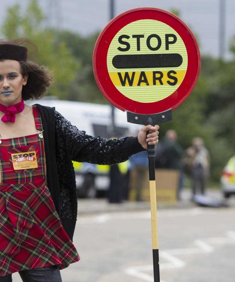 A person holds a street sign reading "stop wars"