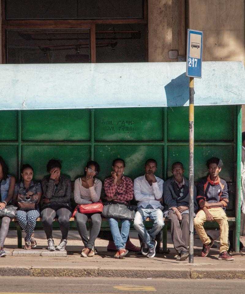 Leute, die an einer Bushaltestelle warten sitzen