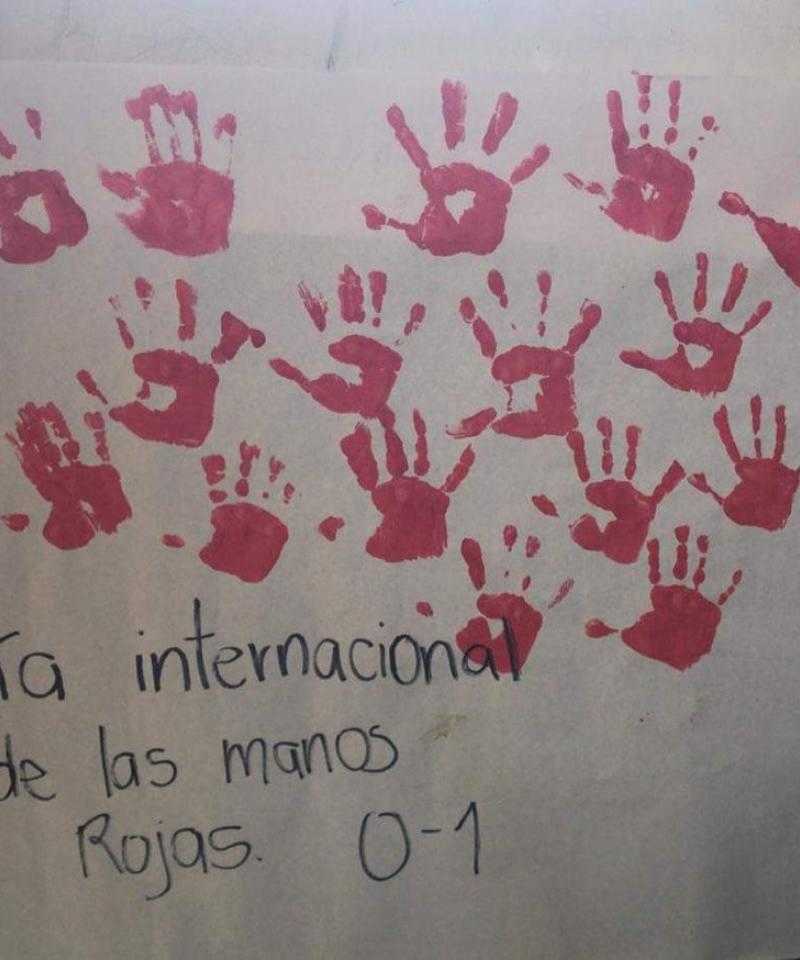 A sign covered in red hands reads "International red hand day" in Spanish