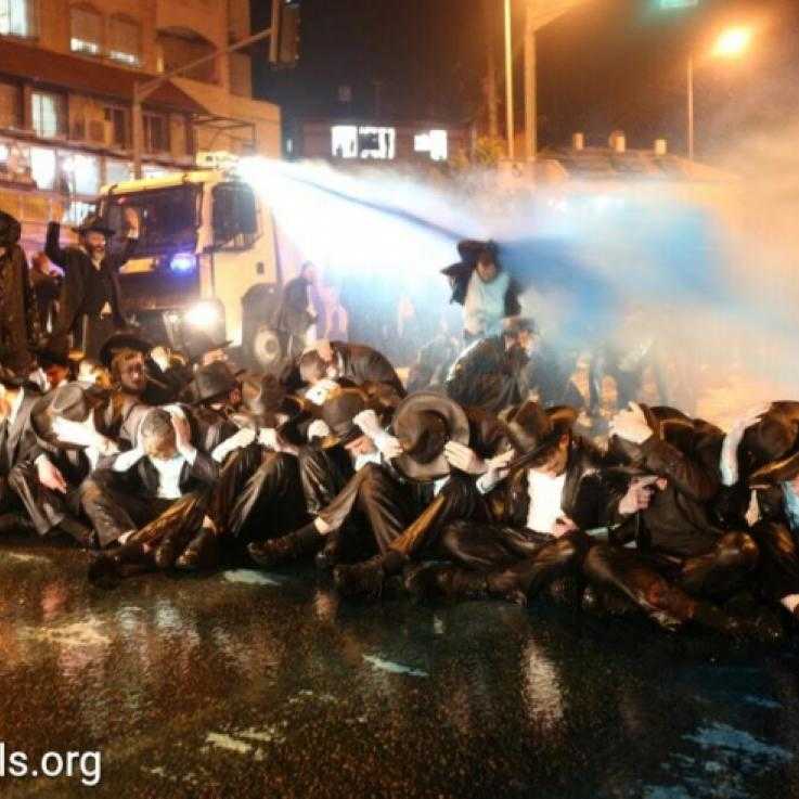 A police van sprays ultra-Orthodox demonstrators with blue liquid during a protest