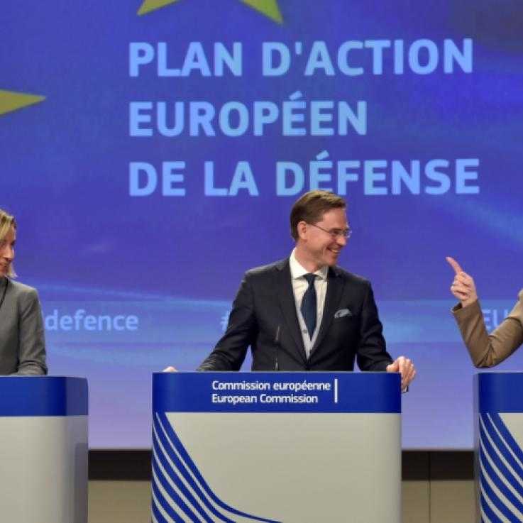 Three politicians stand in front of a sign saying "Plan of Action: European Defence Fund" in French