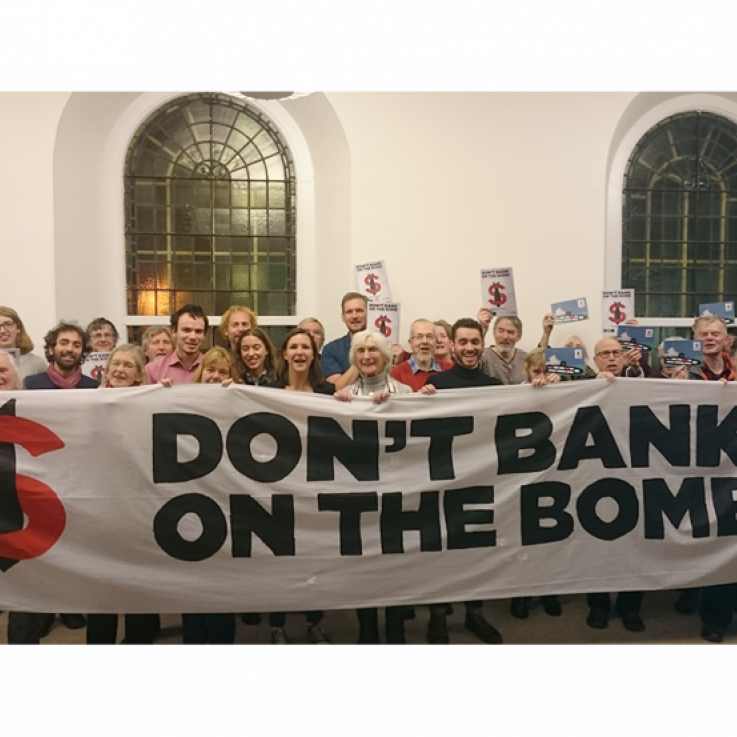 A large number of people standing behind a banner reading "Don't Bank on the Bomb"