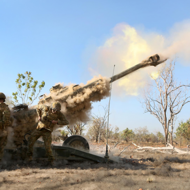 Two soldiers fire a howitzer cannon