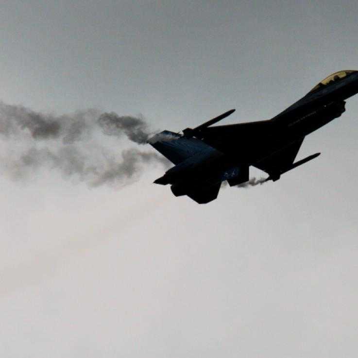 An F16 fighter jet sillhouetted against the sky